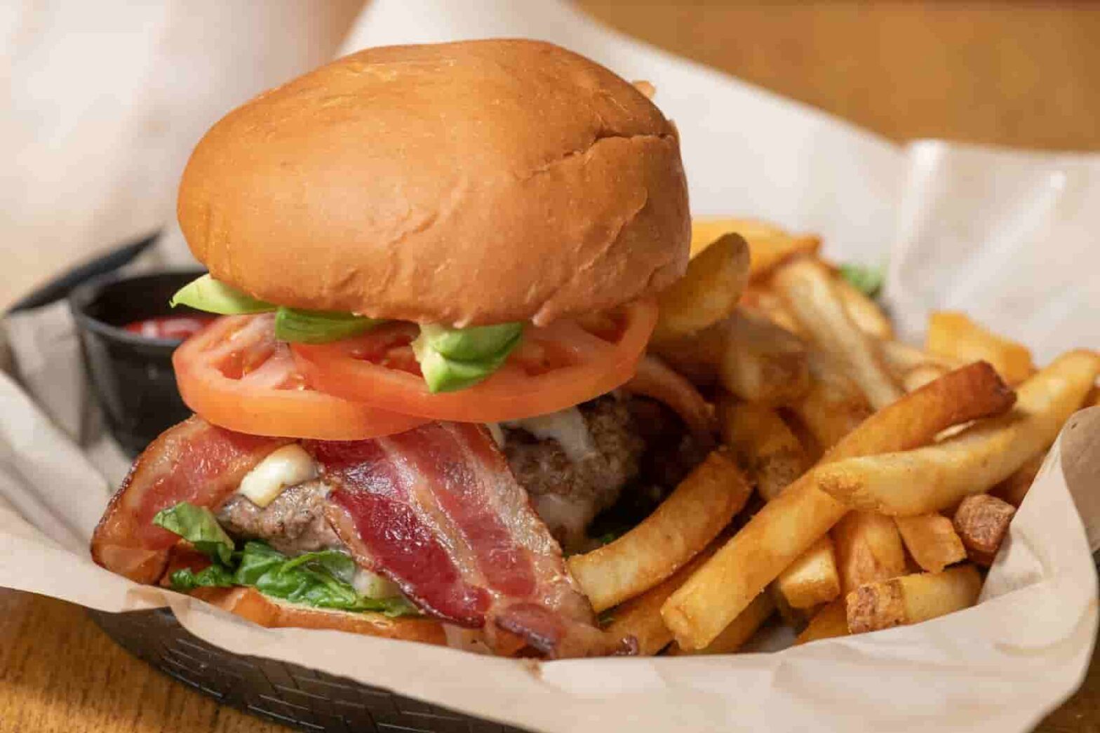 A burger with bacon served with french fries at Crooked Pint Ale House
